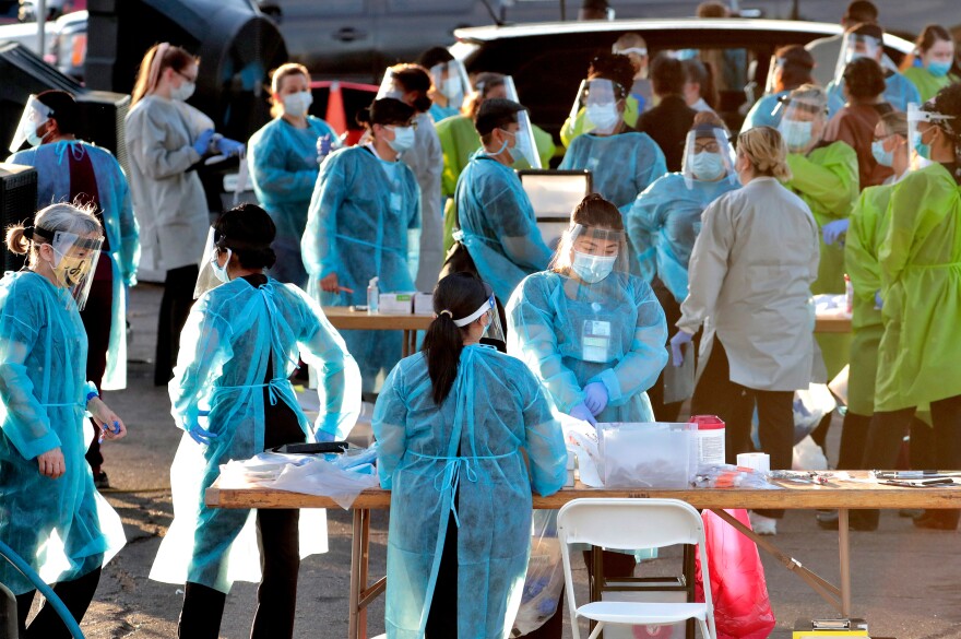 Medical personnel prepare to test hundreds of people for the coronavirus. They lined up in vehicles last week in a Phoenix neighborhood.