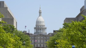 Photo looking down a street with leafy trees toward the Michigan Capitol building.
