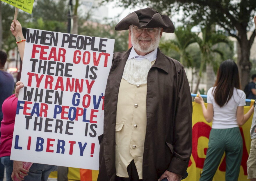 Charles Dockery, a veteran dressed as a founding father, walks through downtown Orlando during the No Kings Day rally. Dockery said his father, grandfather and great-grandfather served in uniform, and he takes the Constitution seriously.