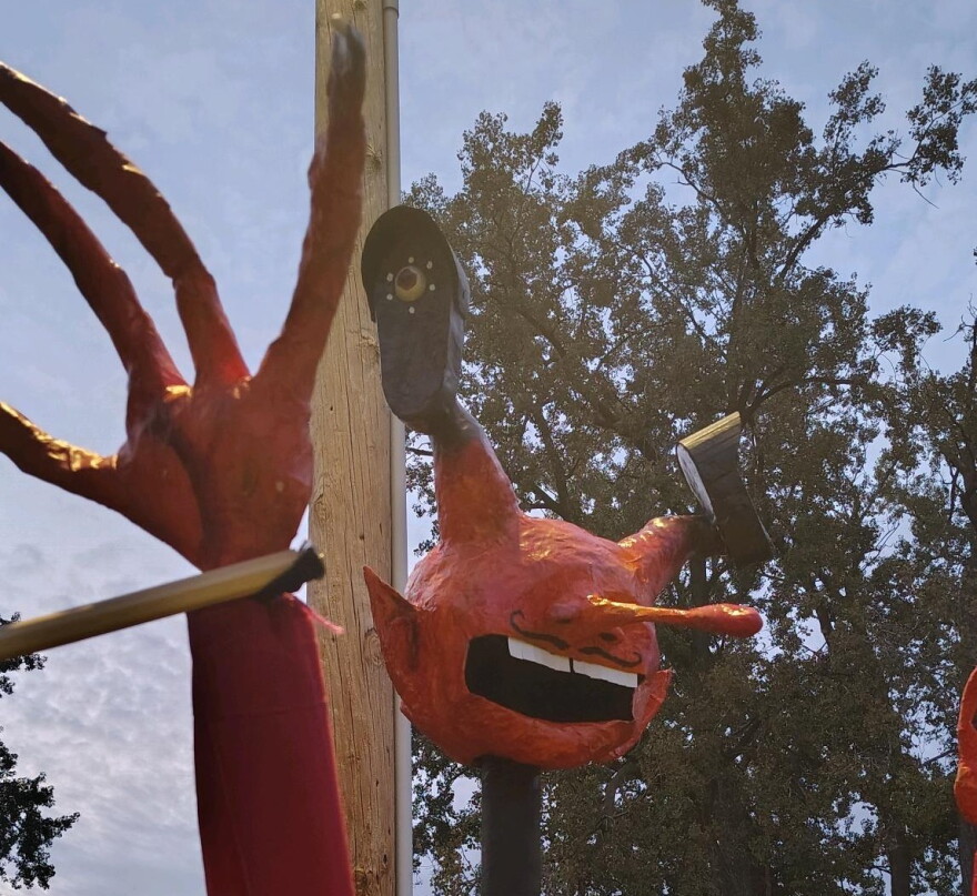 A photo of a puppet head made out of papier-mâché that's made to look like a devil with Flock Safety camera for eyes.