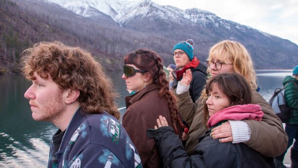 Staff wave goodbye to Holden Village from the departing boat