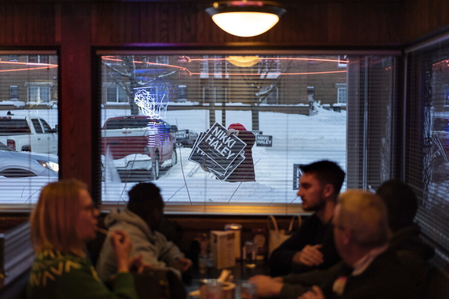 A campaign worker moves signs in front of Drake Diner in Des Moines, Iowa on Monday.