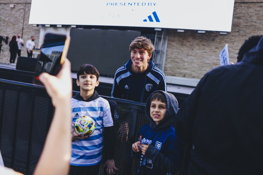 A player from Sporting KC poses with two young fans for a picture.