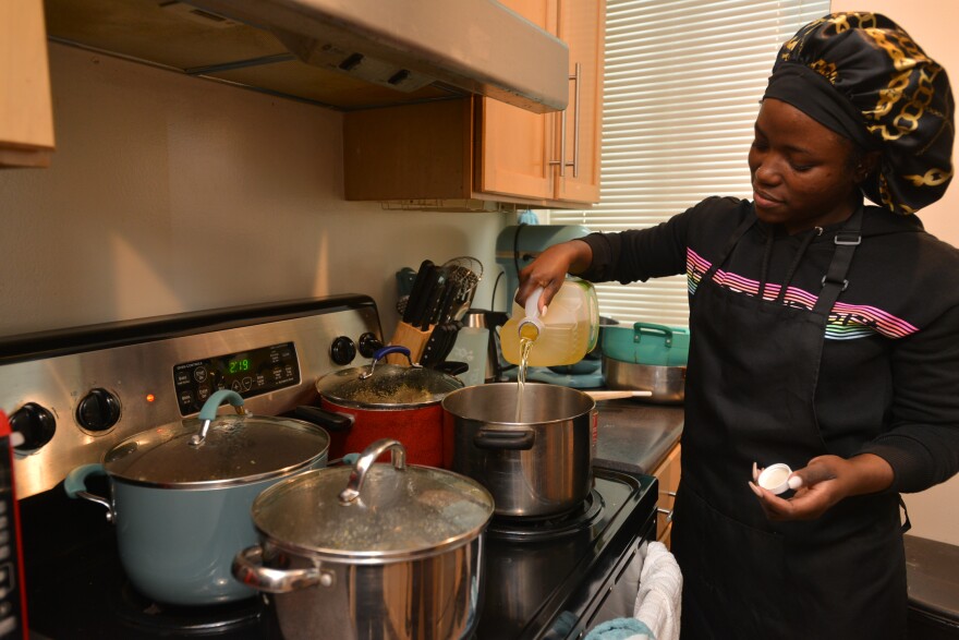 Akinjole adds vegetable oil to a pot. When she's catering, her kitchen fills up fast as she works on multiple dishes at once.