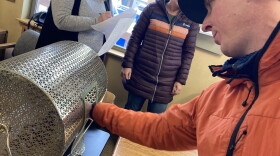 Kevin Jordan leans over to place his lottery tickets in a golden hopper that turns with a large handle on the side.