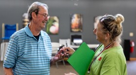 Dave Tanner takes an "I Voted" sticker from election judge Cathy Dietrich at Woodrow Town Hall on Primary Election Day, Aug. 11, 2026.