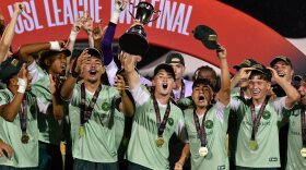 Vermont Green FC players celebrate their 2026 USL2 national championship with hats, medals and the trophy.