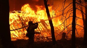 A Cal Fire firefighter sprays water on a home next to a burning home as the Camp Fire moves through the area on Nov. 9, 2018 in Magalia, Calif. (Justin Sullivan/Getty Images)