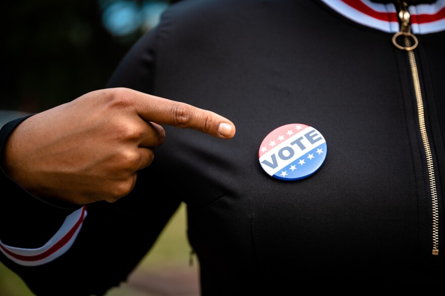 Woman Pointing At A Vote Button Pinned To Her Sweater