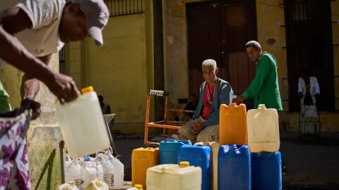 A man fill containers with potable water during a blackout in Havana, Sunday, March 22, 2026.