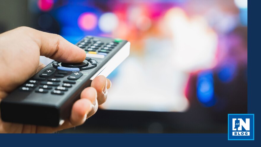 Person holding remote control in front of television screen