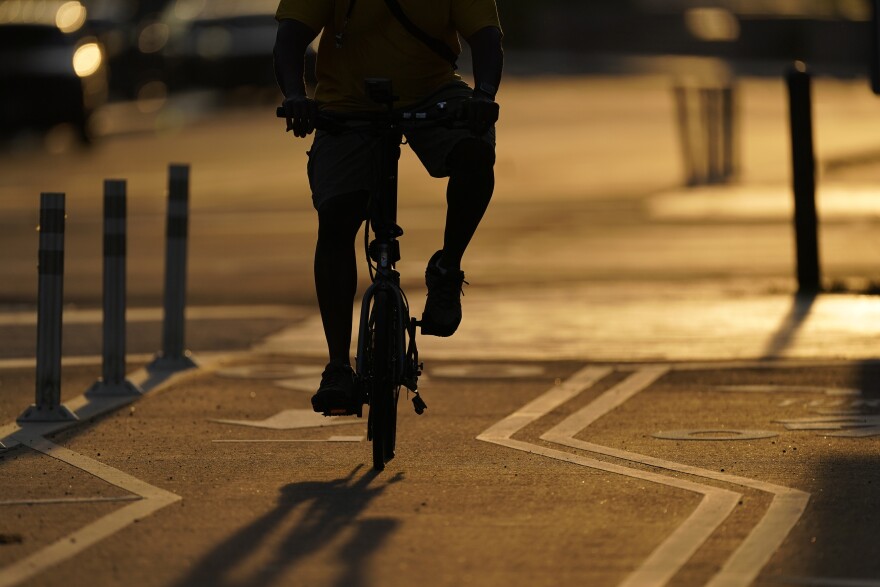 FILE - The sun sets behind a cyclist in a bike lane on Pennsylvania Avenue in Washington