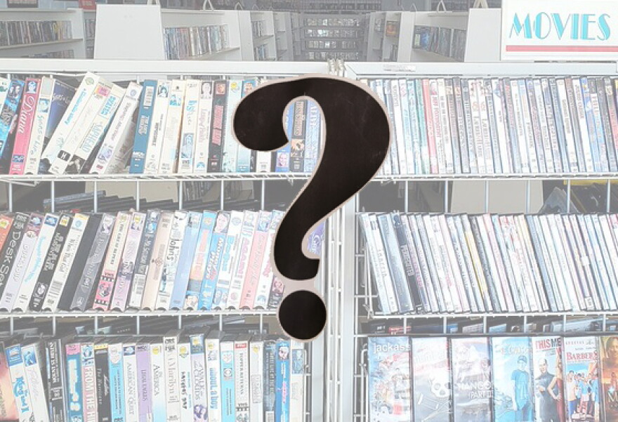 Long shelves of VHS tapes with a question mark in the foreground