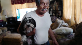 Arturo Gómez, 80, carries one of his three dogs through his home in July in La Lomas Colonia in Rio Grande City, Texas, where they all suffer from the rising temperatures and high cost of electricity.