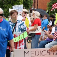 Protesters march down Main Street holding signs and American flags during the No Kings protests on Saturday, June 14, 2025, at the Cooper County Courthouse in Boonville, Mo. The demonstration was part of a national day of action against authoritarianism and political repression.