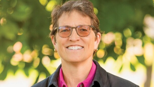 A person with glasses smiles at the camera. 