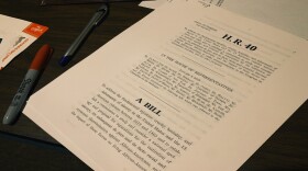 Event goers pick up packets of Congress bill before sitting down to discuss reparations.