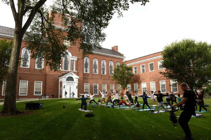 Dartmouth College students and faculty follow yoga instructor Laura Beth "LB" White, the assistant director of the Student Wellness Center, on the Baker Library lawn on Wednesday, Sept., 19, 2023, in Hanover, N.H. A camera crew, who had been following new Dartmouth president Sian Leah Beilock, captured a few minutes of the class. (Valley News - Jennifer Hauck) 