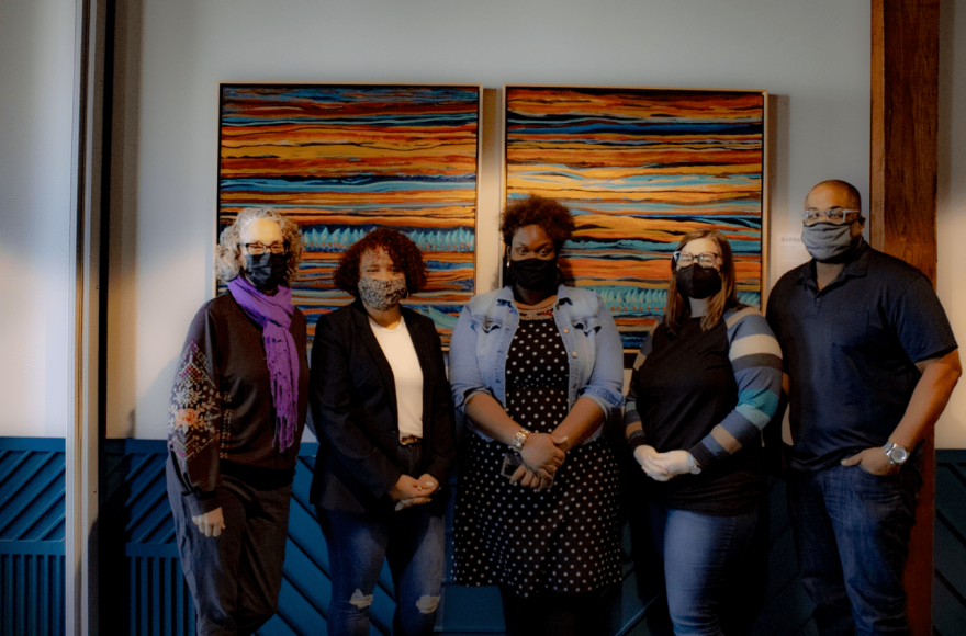 The 2022-2024 InSightFull Business Accelerator cohort from left to right: Julia Youngblood of Youngblood Harmonizing Arts, Robin Garner of Robin G. Poetry, Marlesha S. Woods, National Equity in Arts Director of Lodgic Everyday Community, Airlea Williams & Ian Williams of Reconcile Consulting. Artwork in the background by Barbara Tyson Mosley.