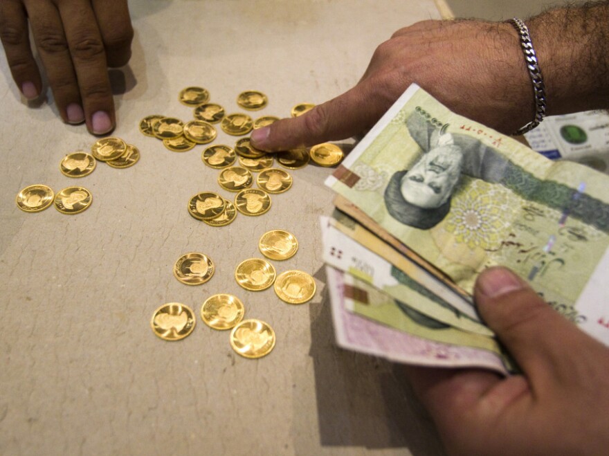 A customer buys Iranian gold coins at a currency exchange office in Tehran. The loss in the rial's value has led Iranians to take their money out of the country — even by speedboat across the Persian Gulf.