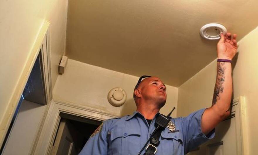 Indianapolis firefighter Derek Huff installs a smoke detector in a home on North Sherman Drive Tuesday.