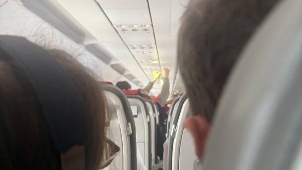A passenger holds an IV saline bag above the aisle as medical volunteers respond to an in-flight emergency aboard a flight approaching Ben Gurion Airport near Tel Aviv, Israel, on October 17, 2026. The aircraft encountered turbulence as passengers and crew worked to stabilize a woman experiencing difficulty breathing.