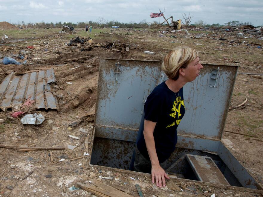 Christie England, an acquisition law paralegal with the 72nd Air Base Wing, based at Tinker Air Force Base, Okla., stands in her storm shelter in front of the remains of her home in Moore, Okla., May 27, 2013, a week after an EF5 tornado with winds exceed