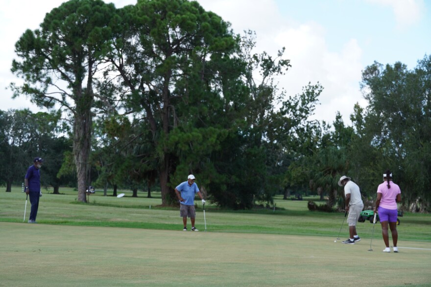 People can be seen golfing at Rogers Park. 