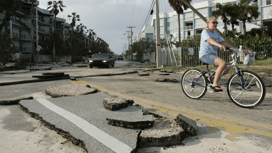 A cyclist rides past buckled asphalt in Key West, Fla., after Hurricane Wilma in 2005. Key West experienced widespread flooding with the storm surge.