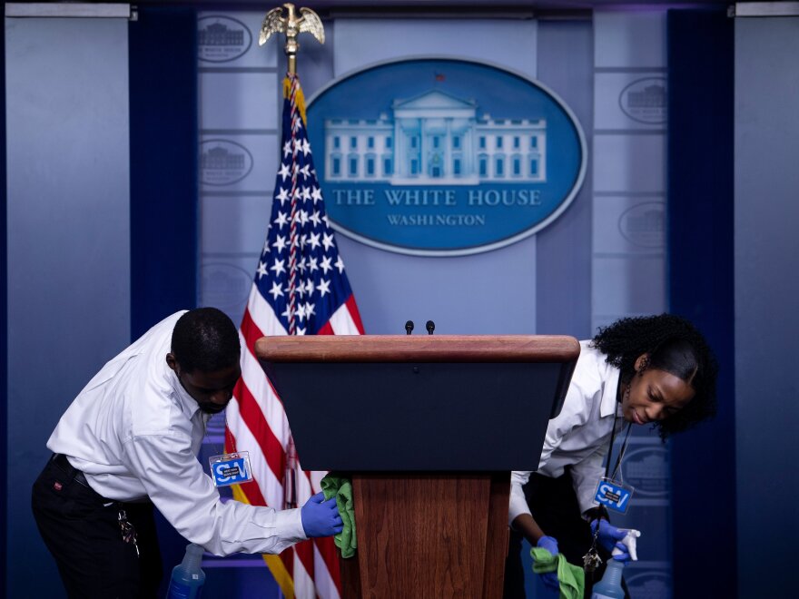 Cleaners sanitize the lectern in the White House briefing room after a coronavirus briefing on March 16, the day Trump announced his 15-day guidelines.