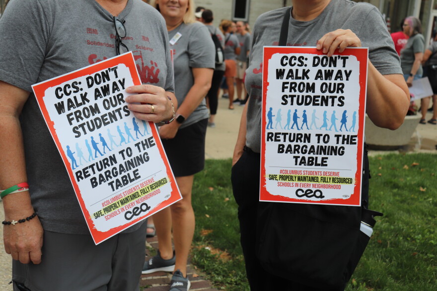 Union members hold protest signs outside school board. They read, CSS: Don't walk away from out students, return to the bargaining table.