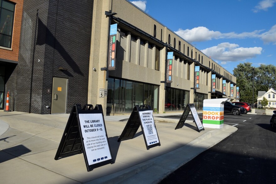 White sandwich board signs sit on the sidewalk of the Bloomington Public Library. The signs tell visitors "The library will be closed Oct. 9-15."