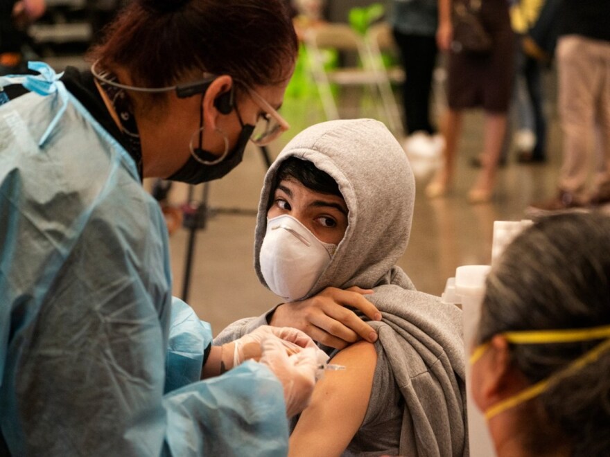 In this May 24, 2021, file photo, a student looks back at his mother as he is vaccinated at a school-based COVID-19 vaccination clinic for students 12 and older in San Pedro, Calif.