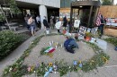 Candles, flowers and photos outside building. 
