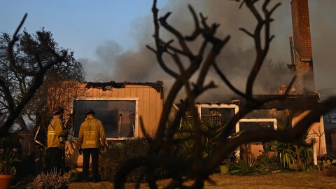 Firefighters look over a home after the Eaton Fire burns in Altadena on Jan. 9, 2025.