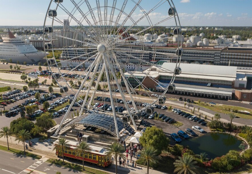 Close-up of a tall ferrris wheel with cruise ships in the background