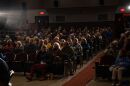 An audience in theater seats watching a screen