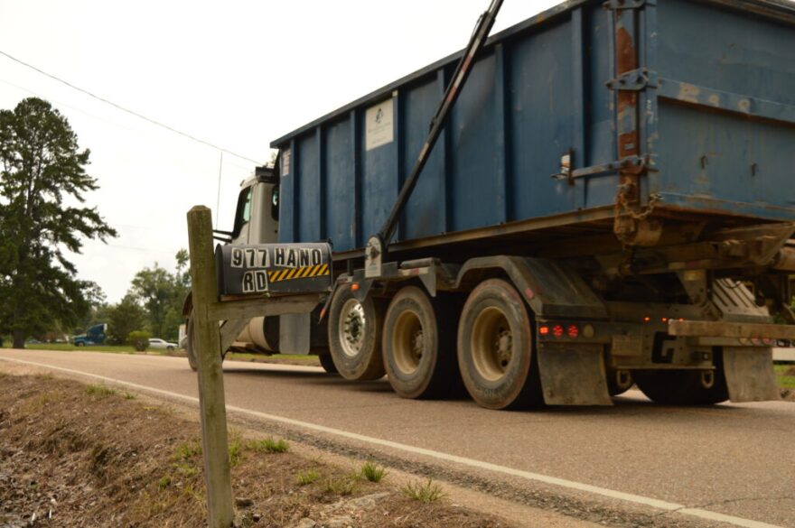 A gravel hauling truck passes homes on Hano Road in St. Helena Parish.