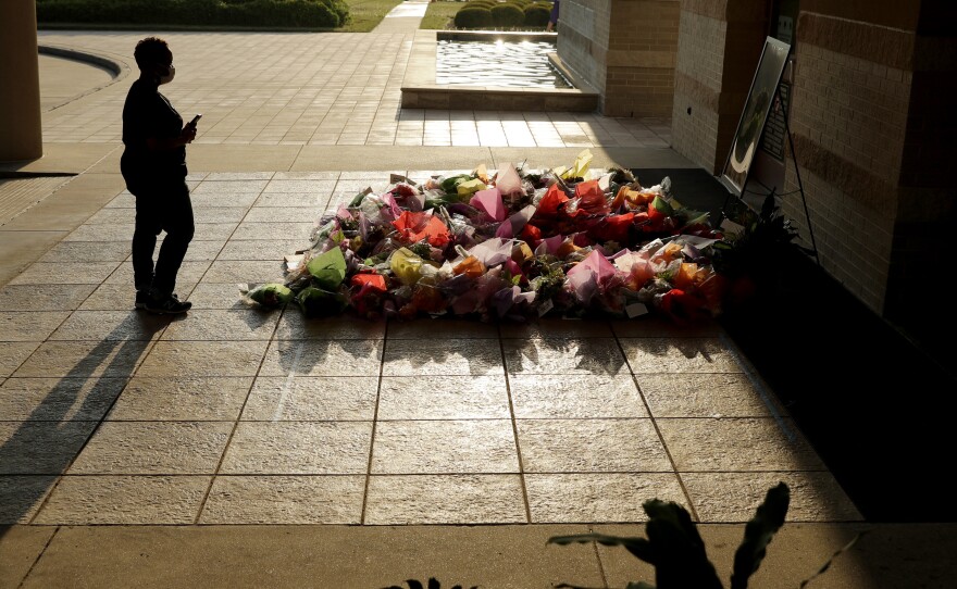 A woman stops to photograph a memorial Tuesday for Floyd at The Fountain of Praise church in Houston.