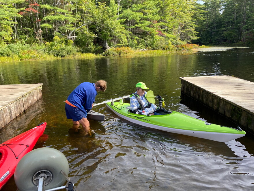 Cathy Webster assists a paddler in launching their adaptive kayak into Fish Creek.