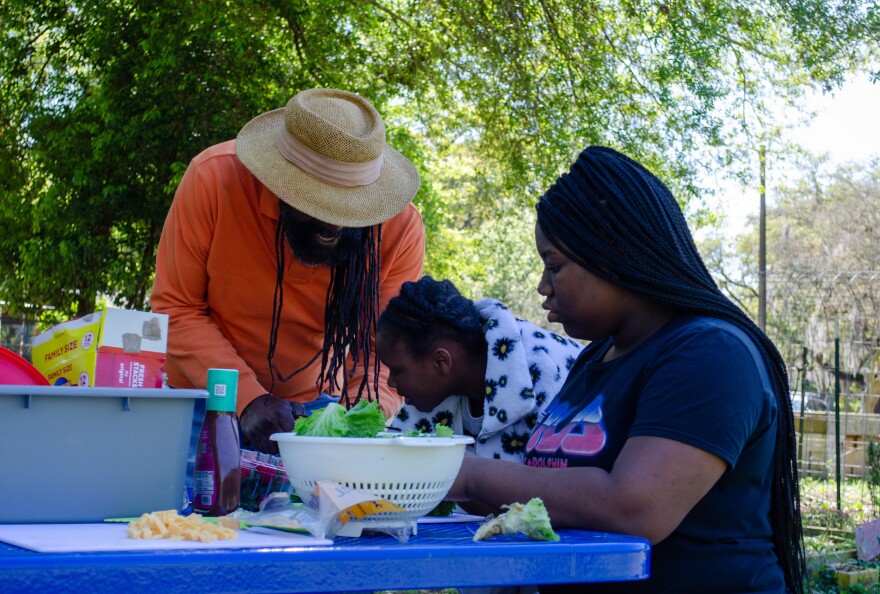 Andrew Miles (left), Alayshia Owens (middle) and Morgan Williams (right) discover a snail hiding in their lettuce as they prepare salads at the community garden at 2444 NE 12 Ave. Gardening has been a big part of Out East's curriculum, Miles said (Matthew Cupelli/WUFT News).