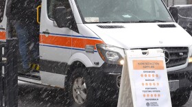 Person at the side of a van with opioid and drug harm reduction supplies, syringes, Narcan, fentanyl testing strips.