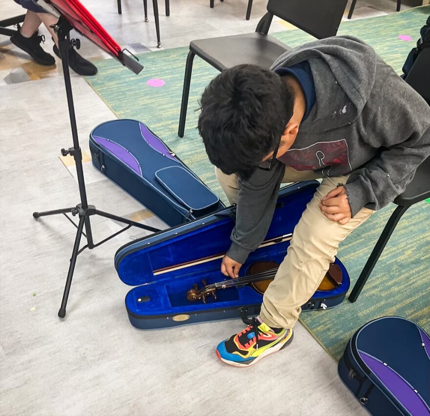 Jefferson, a 5th grade student at Abbottston Elementary School in Baltimore, gets his violin out for class. (Bri Hatch/WYPR)