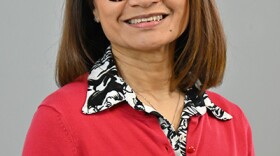 A woman wearing a red sweater poses smiling for the camera.