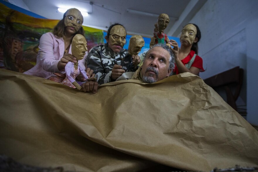 Pedro Adorno, front, and a portion of his Agua, Sol, y Sereno theater company rehearse a portion of their show,"Corazón de Papel: A Hurricane Story," a portrayal of the post-Maria disaster. (Jesse Costa/WBUR)