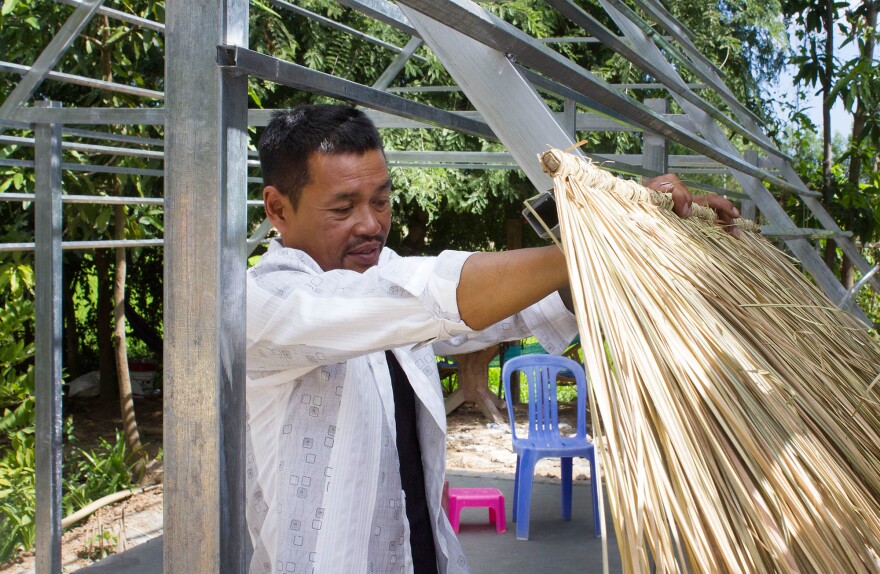 Nheb Thai, one of the deportees, attaches a thatched roof to his pizza hut.