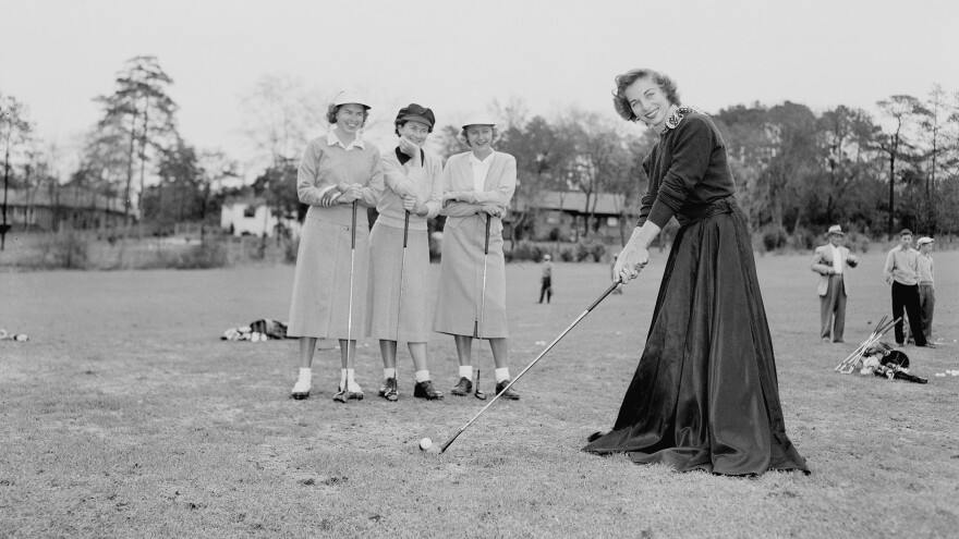 A golfer wears a long black skirt in mock protest of the USGA ban on golfing shorts in tournament play, 1953.