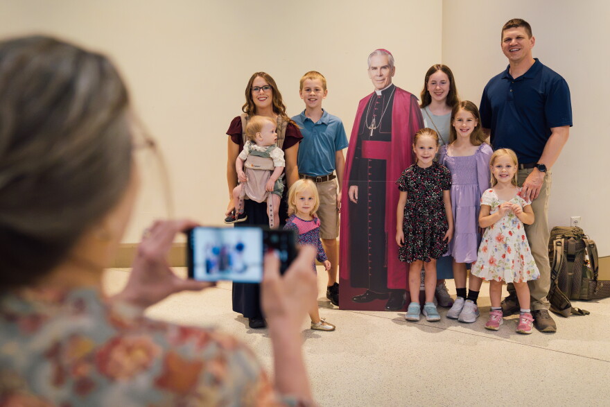 Theresa Meister, of Peoria, Ill., photographs her son Andrew Meister, right, his wife, Tricia Meister, and their children, the family of Hershey, Pa., with a cutout of the late Archbishop Fulton J. Sheen ahead of Sheen's beatification Mass on Thursday at the Dome at America's Center in downtown St. Louis. The couple's youngest child, 15-month-old Fulton, was named after Sheen.