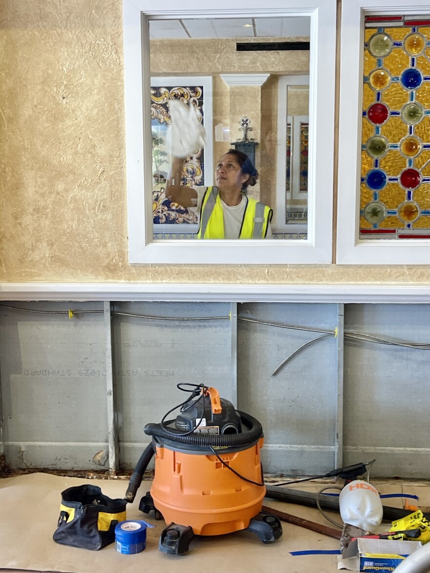 A woman in a yellow cleans an interior window at the Columbia restaurant