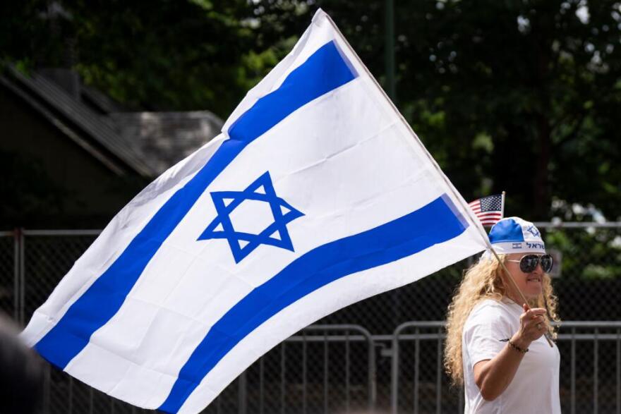 A woman holds an Israeli flag while walking down Fifth Avenue during the Israel Day Parade, Sunday, May 31, 2026, in New York. (Emil T. Lippe/AP)